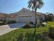 Tan two-car garage home with palm tree and American flag at 1890 San Trovaso Way, Venice, FL 34285