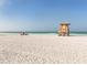 Peaceful beach scene featuring a lifeguard stand and a red beach umbrella at 2020 Harbourside Dr # 424, Longboat Key, FL 34228