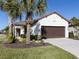 Two-car garage with brown door and landscape at 205 Carlino Dr, Nokomis, FL 34275