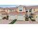 Tan two-story condo with two-car garage, landscaping, and brick driveway at 23253 Banbury Way, Venice, FL 34293