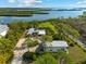 Aerial view of property featuring a main house, a storage building, lush landscaping and waterfront at 38 Riverfront Dr, Venice, FL 34293