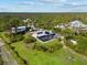 Aerial view of a modern home featuring a screened-in pool, set amidst a landscape of verdant trees and expansive lawn at 38 Riverfront Dr, Venice, FL 34293