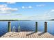 Wooden dock over the water complete with a metal ladder for easy water access and blue skies at 38 Riverfront Dr, Venice, FL 34293
