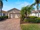 Single-story house with tan walls and a tile roof, featuring a brick driveway and landscaping at 482 Montelluna Dr, North Venice, FL 34275
