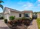 Tan house with tile roof and gray shutters, showcasing a brick walkway and landscaping at 482 Montelluna Dr, North Venice, FL 34275