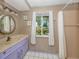 Charming bathroom featuring a vanity, decorative mirror, and a window view of lush landscaping at 601 E Seminole Dr, Venice, FL 34293