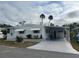 Front view of a white manufactured home with covered patio and palm trees at 607 Cervina Dr, Venice, FL 34285