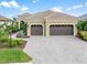 Two-car garage, paver driveway, and manicured lawn at 10984 Trevino St, Englewood, FL 34223