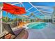 Inviting screened pool with lounge chairs and umbrella at 1815 Killdeer Ct, Venice, FL 34293