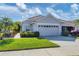 Tan house with two-car garage, lush landscaping, and a paved walkway at 1891 San Silvestro Dr, Venice, FL 34285