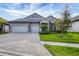 Two-story house with gray siding, three-car garage, and landscaped yard at 19807 Bridgetown Loop, Venice, FL 34293