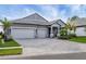 Two-story house with gray siding, three-car garage, and landscaped yard at 19807 Bridgetown Loop, Venice, FL 34293