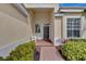 Covered entryway with gray door, brick walkway, and lush landscaping at 2136 Mesic Hammock Way, Venice, FL 34292