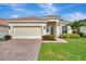 Single-story home with a beige exterior, two-car garage, and well-manicured lawn at 2136 Mesic Hammock Way, Venice, FL 34292