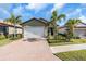 Single-story house with a two-car garage, landscaping and a brick driveway at 232 Teramo Way, Nokomis, FL 34275
