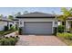 House exterior featuring a gray garage door, brick driveway and landscaping at 2751 Lavandula Ct, North Port, FL 34289