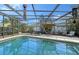 Screened-in pool with patio furniture, umbrella, and built-in grill at 518 Boxwood Ln, Englewood, FL 34223