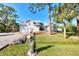 White two-story house with a large yard, palm trees, and a paved driveway at 668 Alligator Dr, Venice, FL 34293