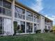 Exterior view of the condo with a large balcony and screened-in porch with a lush lawn at 801 Waterside Dr # 102, Venice, FL 34285