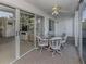 Bright lanai with glass sliding doors, seating for four, and a ceiling fan at 801 Waterside Dr # 102, Venice, FL 34285