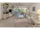 Comfortable living room with neutral carpet, ceiling fan, and sliding glass doors to the lanai at 801 Waterside Dr # 102, Venice, FL 34285