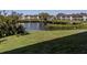 Community pond view with lush green grass and mature trees at 801 Waterside Dr # 102, Venice, FL 34285
