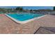Community pool with brick patio and lounge chairs at 801 Waterside Dr # 102, Venice, FL 34285
