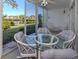 Enclosed sunroom features a glass table and offers picturesque views of the lake and landscaped grounds at 801 Waterside Dr # 102, Venice, FL 34285