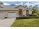 Tan stucco home with white garage door, landscaping, and arched entryway at 826 Bayport Cir, Venice, FL 34292