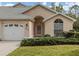 Tan stucco home with white garage door, landscaping, and arched entryway at 826 Bayport Cir, Venice, FL 34292