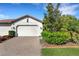 Two-car garage with a brick paved driveway and attractive landscaping at 9824 Haze Dr, Venice, FL 34292