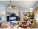 Bright living room with comfy sofas, a large TV, and a ceiling fan at 104 Woodingham Dr, Venice, FL 34292