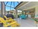 Spacious screened lanai with yellow chairs, a grill and view of backyard at 11409 Okaloosa Dr, Venice, FL 34293