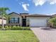 Single story home with green exterior, brick paver driveway, and landscaping at 11945 Lovegrass St, Venice, FL 34293