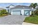 Two-story house with light-colored siding, light blue garage doors, and a paver driveway at 12460 Davie Ct, Venice, FL 34293