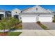 Two-car garage, gray exterior, landscaping, and a paved driveway at 12488 Palatka Dr, Venice, FL 34293