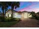 Attractive tan house with tile roof, white garage door, and landscaped yard at dusk at 13240 Guyana St, Venice, FL 34293