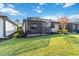 Backyard view showcasing a screened porch and lush lawn at 13864 Posada St, Venice, FL 34293