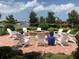 Stone fire pit surrounded by white Adirondack chairs on a brick patio at 13864 Posada St, Venice, FL 34293