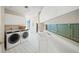 Bright laundry room with white cabinets, washer, dryer, and window at 213 The Esplanade S, Venice, FL 34285