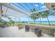 Covered patio overlooking the ocean with wicker chairs and tropical landscaping at 213 The Esplanade S, Venice, FL 34285