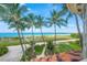 Balcony view of the ocean and beach with lush tropical foliage at 213 The Esplanade S, Venice, FL 34285