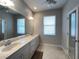 Main bathroom with double vanity, large mirror, and tile flooring at 2890 Whispering Pine Ln, North Port, FL 34287