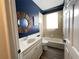 Bathroom with tub, vanity, and dark blue accent wall at 2890 Whispering Pine Ln, North Port, FL 34287