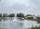 Serene lake view featuring a water fountain and community homes at 2890 Whispering Pine Ln, North Port, FL 34287