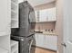 Laundry room with stackable washer and dryer, white cabinets, and patterned wallpaper at 400 Maraviya Blvd, Nokomis, FL 34275