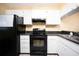 Kitchen boasts black appliances and white cabinets at 408 Cerromar S Cir # 132, Venice, FL 34293