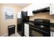 Kitchen with black appliances, white cabinets and a view of the dining area at 408 Cerromar S Cir # 132, Venice, FL 34293