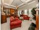 Home library with built-in bookshelves and red chairs at 441 Tremingham Way, Venice, FL 34293