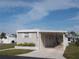 Tan mobile home with carport, landscaping, and partial view of neighboring homes at 516 Ashwood Dr, Venice, FL 34285